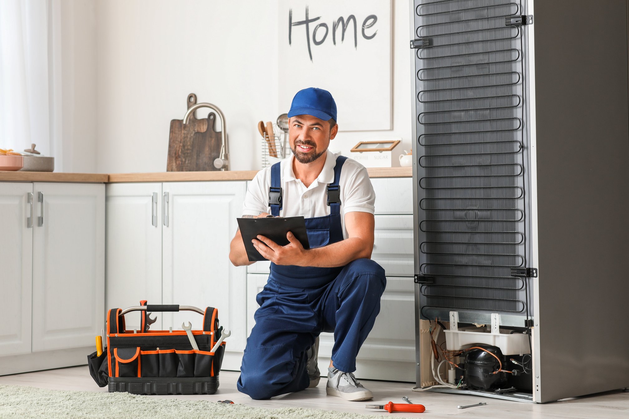 Worker Repairing Fridge in Kitchen